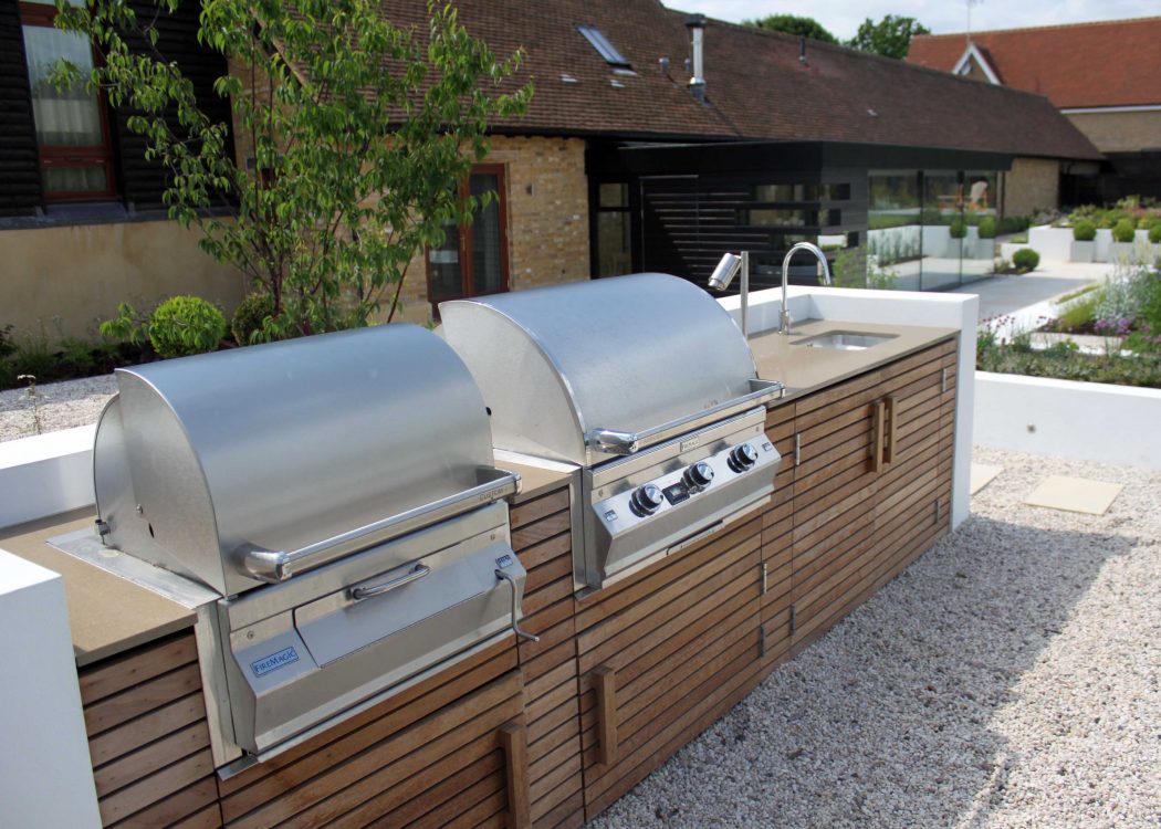 two stainless steel fire maggic bbqs in a wooden outdoor kitchen unit